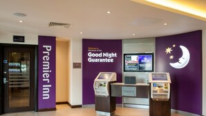 A check-in area at Premier Inn with a purple wall, a digital kiosk, and a sign indicating the location of lifts and stairs. - Premier Inn Worcester City Centre (Worcester)