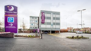 Een Premier Inn hotel met een parkeersbord, een parkeerplaats voor gasten en een moderne gevel.