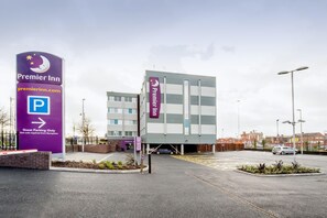 Ein Premier Inn Hotel mit Parkschild, gekennzeichnetem Parkbereich für Gäste und einer modernen Fassade.