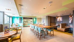 Een moderne hotel lobby met een lange receptiebalie, zithoeken en een uitzicht op de stadshemel.