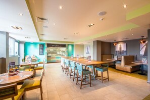 A modern hotel lobby with a long reception desk, seating areas, and a view of the city skyline. - Premier Inn Birkenhead Town Centre (Birkenhead)