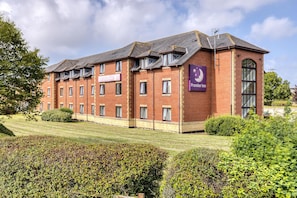 A brick building with a sign for Premier Inn, multiple windows, and a well-maintained lawn. - Premier Inn Blackpool East - M55 J4 (Blackpool)