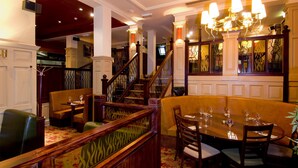 A dining area with a wooden staircase, cushioned seating, and a chandelier. - Premier Inn Christchurch - East (Christchurch)
