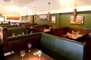 A restaurant interior with booths, tables, and hanging pendant lights. - Premier Inn Christchurch - East (Christchurch)