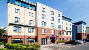 A multi-story hotel with a prominent 'Premier Inn' sign, a parking lot with several cars, and a clear blue sky. - Premier Inn Bournemouth Westbourne (Bournemouth)