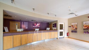 A hotel reception area with a counter, a sign for Premier Inn, and a fire extinguisher on the wall. - Premier Inn Bournemouth Westbourne (Bournemouth)