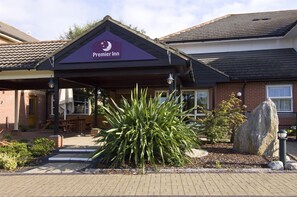 Een Premier Inn met overdekte ingang, terras en een grote plant op de voorgrond.