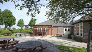 An outdoor patio area with picnic tables, a covered seating area, and a brick building. - Premier Inn Bristol South (Bristol)