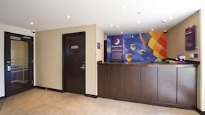 A hotel reception area with a reception desk, a wall with a colorful mural, and a door labeled 'Rooms 1-120'. - Premier Inn Bristol South (Bristol)