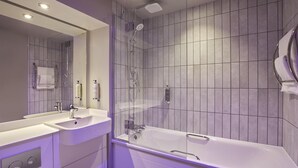 A modern bathroom with a bathtub, two sinks, a shower, and a large mirror. - Premier Inn Skipton North - Gargrave (Skipton)