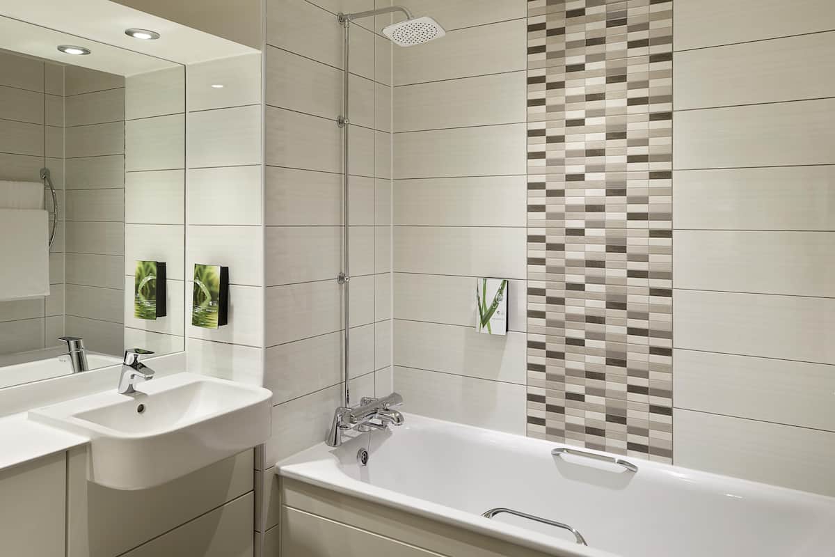 A modern bathroom with two sinks, a bathtub, and a shower.