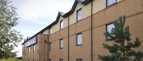 Un immeuble à plusieurs étages, doté d’une façade en briques, de nombreuses fenêtres et d’une enseigne indiquant qu’il s’agit d’un hôtel.