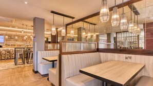 A restaurant with booths, hanging pendant lights, and a bar area with bottles. - Premier Inn Bristol Cribbs Causeway - M5 J17 (Bristol)
