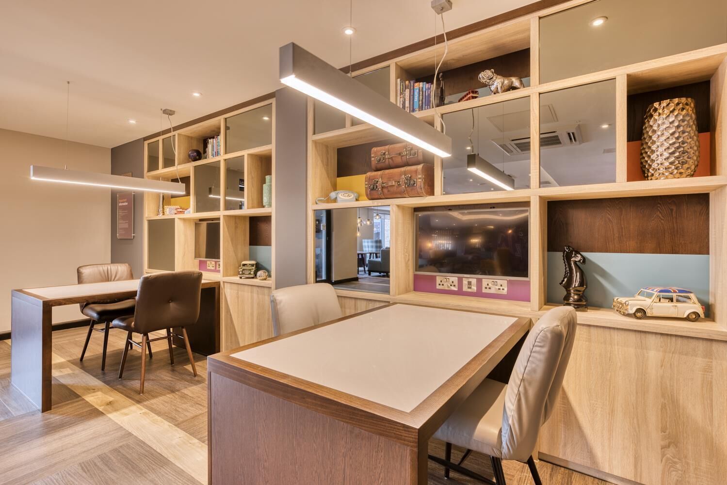 A modern room with a wooden desk, chairs, and built-in shelves with books and decorative items.