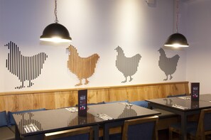 A restaurant interior with wooden paneling, black tables, and hanging pendant lights. - Premier Inn Halifax Town Centre (Halifax)