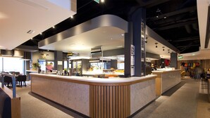 A modern interior with a curved reception desk, seating area, and a visible staircase. - Premier Inn Halifax Town Centre (Halifax)