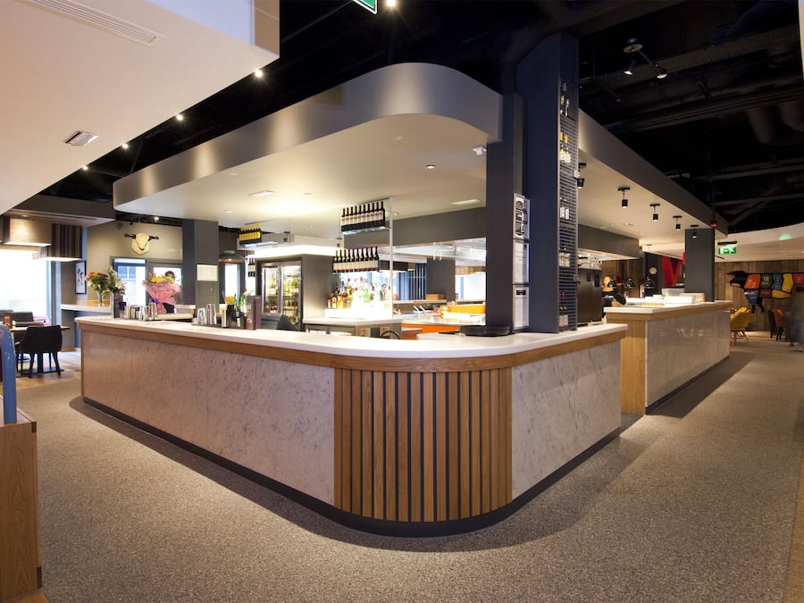 A modern interior with a curved reception desk, seating area, and a visible staircase.
