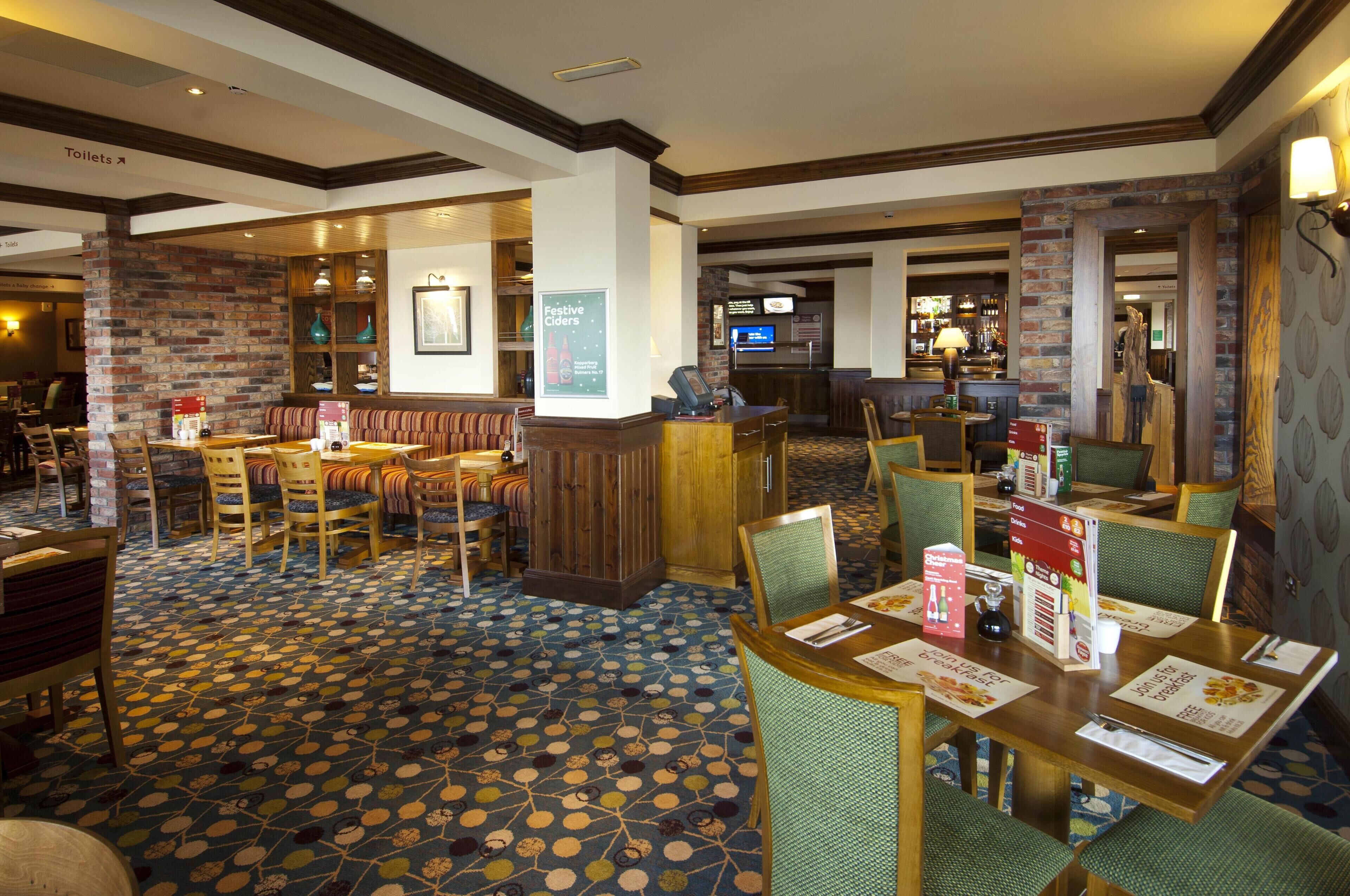 A hotel lobby with a brick wall, wooden reception desk, and seating area.