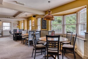 A dining area with round tables, chairs, and a hanging copper pendant light. - Premier Inn Arundel (Arundel)