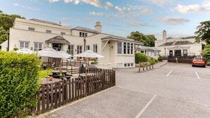 A hotel with outdoor seating, a wooden fence, and a parking area. - Premier Inn Arundel (Arundel)