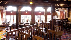 A restaurant with wooden tables and chairs, large windows, and hanging light fixtures. - Premier Inn Eastbourne (Eastbourne)