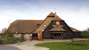 A building with a sign reading 'THE MILL' and a picnic table in front. - Premier Inn Eastbourne (Eastbourne)