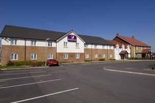 Un hotel Premier Inn con un estacionamiento y un coche rojo aparcado delante.