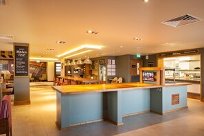 A modern kitchen area with a central island, bar seating, and a dining area with tables and chairs.