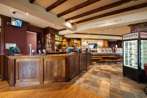 A bar area with wooden counters, a television, and a sign indicating amenities like toilets, disabled access, and a baby change. - Premier Inn Barrow-In-Furness (Barrow-in-Furness)