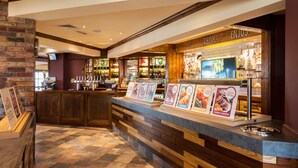 A bar area with a counter, menu boards, and a television screen. - Premier Inn Barrow-In-Furness (Barrow-in-Furness)