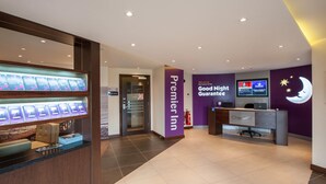 A hotel reception area with a check-in counter, a digital display, and a wall-mounted sign indicating a 'Good Night Guarantee.' - Premier Inn Barrow-In-Furness (Barrow-in-Furness)