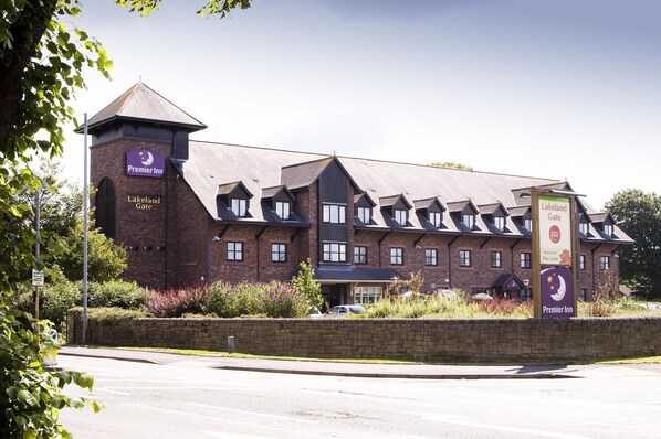 En byggnad i tegel med ett torn, märkt med texten ”Premier Inn Lakeland Gate”, och en skylt som visar var lekplatsen finns.