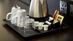Un plateau avec une bouilloire, des tasses, des verres et des en-cas emballés.