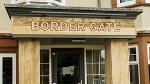 A building entrance with a sign reading 'BORDER GATE,' a dark door, and a small window above the door. - Premier Inn Carlisle - M6 Jct42 (Carlisle)