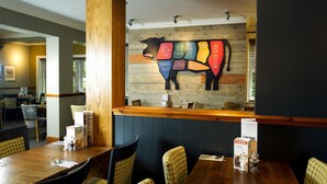 A restaurant interior with wooden walls, a wooden counter, and a menu stand. - Premier Inn Carlisle - M6 Jct42 (Carlisle)