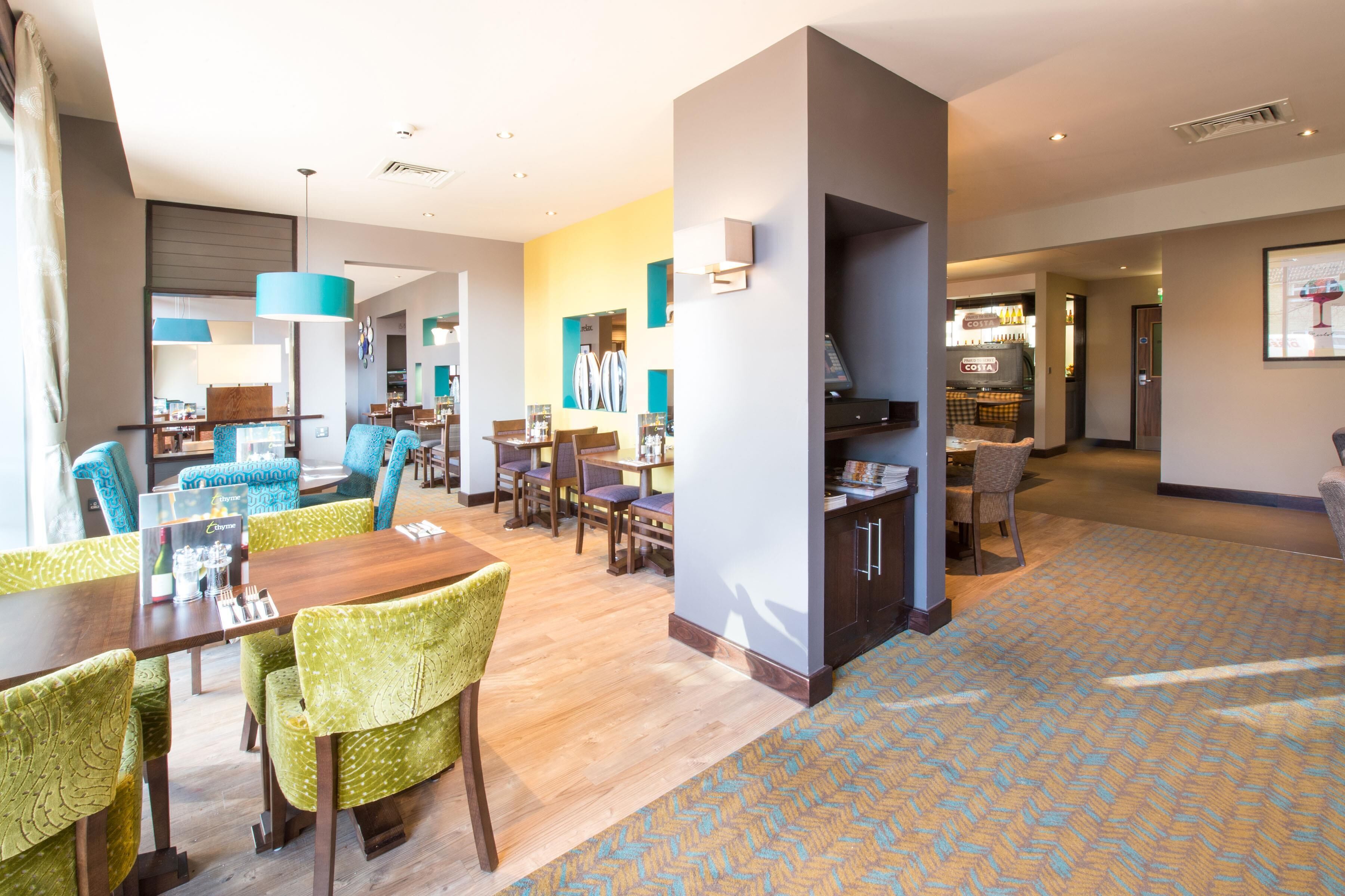 Un moderno vestíbulo de hotel con un comedor, un bar y una cocina a la vista.
