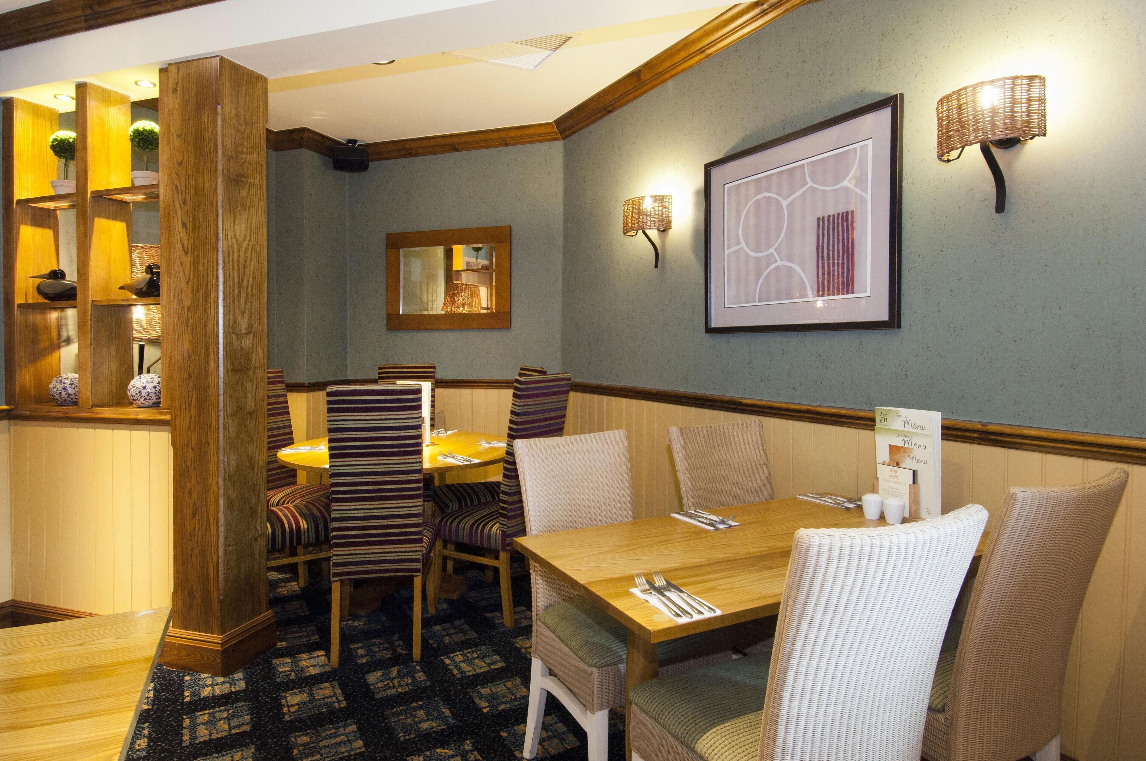 Un comedor con mesa de madera, sillas a rayas y un atril para el menú.