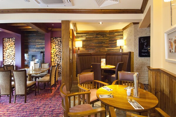 Un restaurant avec des tables et des chaises en bois, des murs en pierre et un mur en briques.