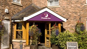Ein Gebäude aus Ziegelsteinen mit einer violetten Markise, auf der 'Premier Inn' steht. Ein Schild empfängt Gäste im Premier Inn in Wrexham.