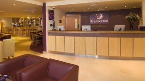 A hotel reception area with a reception desk, a bar, and seating arrangements. - Premier Inn Chester - Railway Station (Chester)