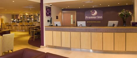 A hotel reception area with a reception desk, a bar, and seating arrangements.