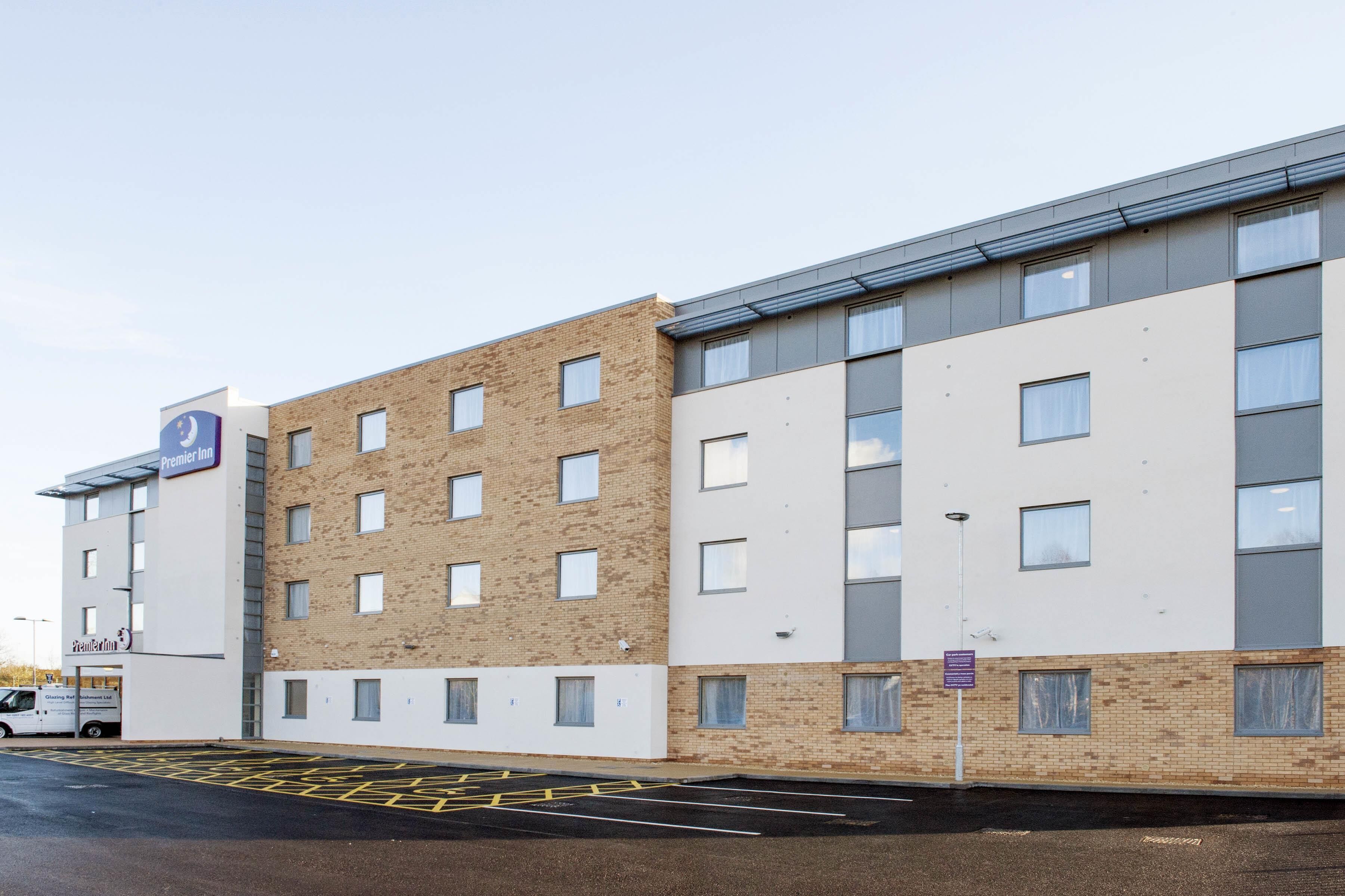 A multi-story hotel with a brick facade, large windows, and a parking area with yellow lines.