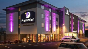 Un hotel Premier Inn con diseño moderno, amplias ventanas y un estacionamiento.
