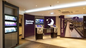 Un hall de hotel con quioscos de autoservicio, una pantalla de televisión y un cartel grande que anuncia el hotel.