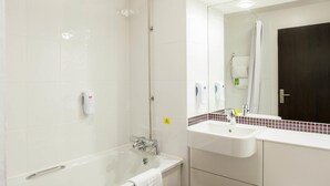Un baño moderno con bañera, ducha, lavamanos y espejo.