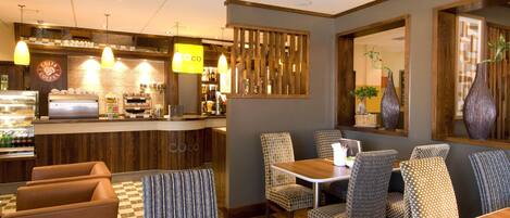 A restaurant with a counter, chairs, tables, and hanging lights.