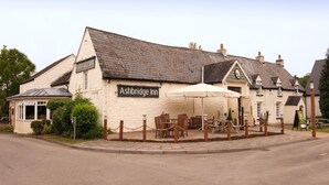 A building with a sign reading 'Ashbridge Inn' and outdoor seating with umbrellas. - Premier Inn Cwmbran (Cwmbran)