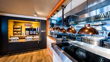 A modern kitchen with stainless steel appliances, a wooden counter, and a sign reading 'PROUD TO SERVE COSTA'.