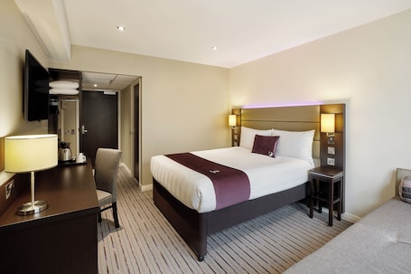 A hotel room with a bed, bedside tables, a desk with a lamp, a chair, and a wardrobe.. Premier Inn Glenrothes