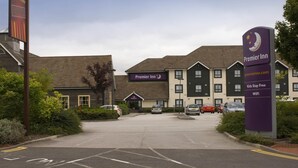 A hotel entrance with a sign for Premier Inn, a parking area, and a building with a brown roof. - Premier Inn Doncaster - Lakeside (Doncaster)